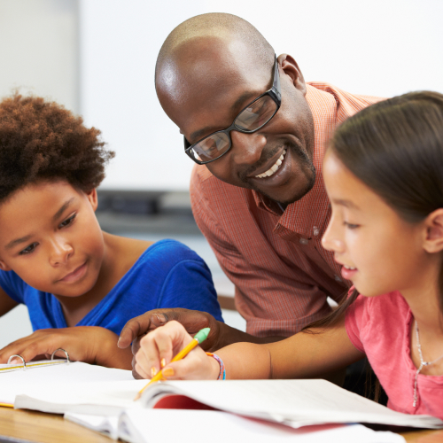 Teacher giving individual assistance to young students